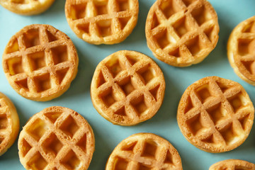 Small round Belgian waffles on blue background. Close up food, top view