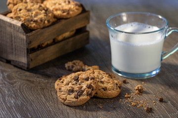 A stack of cookies and a glass of milk on a wooden table 