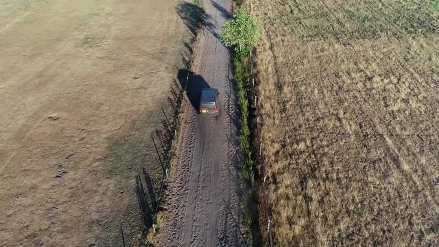 Aerial drone following an off-road truck moving over unpaved dusty way very dry landscape showing dust from soil picked up by wind wasteland located in Africa 4k high resolution footage quality