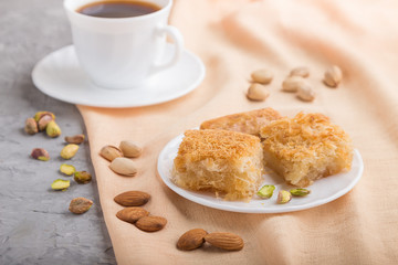 traditional arabic sweets and a cup of coffee on a gray concrete background. side view, selective focus.