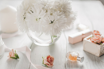 Fototapeta na wymiar Bouquet of white chrysanthemums with women's accessories perfume, lipstick, cream.
