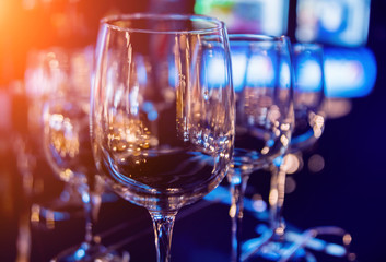 Wine and martini glasses in shelf above a bar rack in restaurant. Empty clean glasses in bar.
