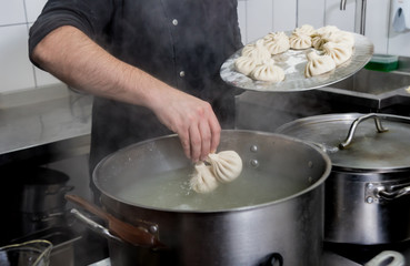 Chef coocking georgian khinkali or japanese wonton. Traditional meal of dough and meat. National cuisine, cooking process. Restaurant kitchen.