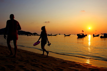 the silhouette picture of tourist are walking on beach to resort in sunset time .