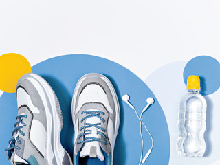 Pair of sport shoes, earphones and water.