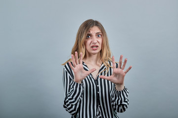 Disappointed blonde woman in fashion black and white striped shirt showing palms at camera, unhappy...