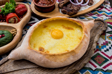 Khachapuri with cheese, vegetables and eggs. Georgian national cuisine. Restaurant.