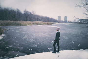 Winter nature landscape trail run runner woman taking a break at frozen lake enjoying scenery of cold winter view. City park background.