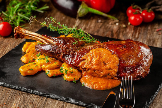 Serbian, Balkan cuisine. Lamb of leg with gnocchi. Serving in a restaurant on a black slate, on wooden table. background image, copy space