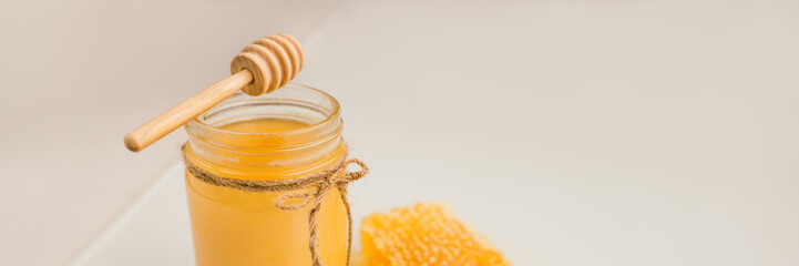 Honey pot with honey dipper and natural honeycomb banner background.
