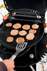 Man grilling steaks on a portable BBQ, Snowy winter barbecue outdoors in the cold . Outdoors winter barbecue party.