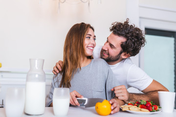 Obraz na płótnie Canvas happy young couple have fun in modern kitchen indoor while preparing fresh fruits and vegetables food salad. Beautiful young couple talking and smiling while cooking healthy food in kitchen at home.