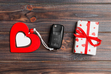 Top view of car key, gift box and heart as a present for Valentine's day on wooden background. Romance concept