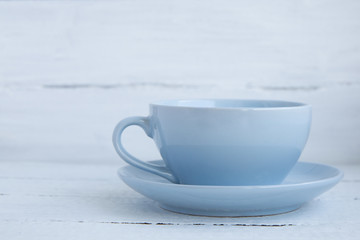 Blue cup and saucer on a white wooden background