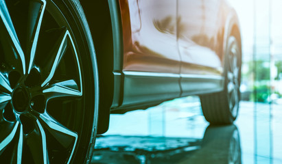 Luxury car parked in modern showroom. Auto leasing business. Car dealership concept. Closeup wheel...