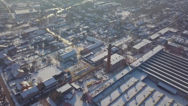 Aerial view of a factory covered in snow in a residential area