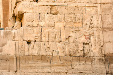 Karnak temple complex in Luxor, Egypt. Ancient bas relief with hieroglyphs on wall, pharaoh and god.