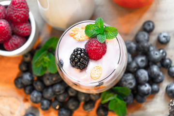 yogurt with whole fresh blueberries raspberries on wooden table. Healthy eating