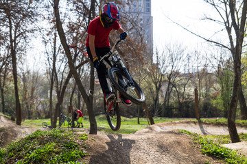 Fototapeta na wymiar An extreme teen kid freestyle jumping on the trial bicycle in the park. 