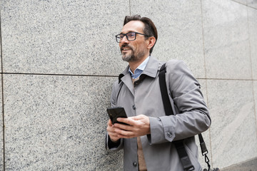 Image of joyful adult businessman using cellphone and laughing