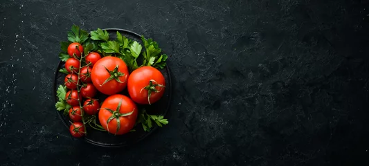 Fotobehang Verse rode tomaten op een donkere achtergrond. Groenten. Bovenaanzicht. Vrije ruimte voor uw tekst. © Yaruniv-Studio