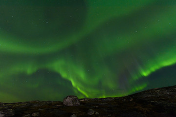 Aurora borealis over the hills. At night in the sky in the north.