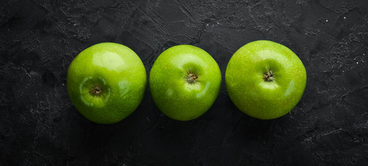 Three fresh green apples on a black stone background. Vegetables. Top view. Free space for your text.