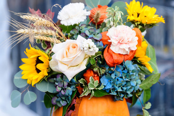 Close up of bouquet of mixed autumn flowers and plant in a glass, displayed for sale at a flower market in a sunny autumn day