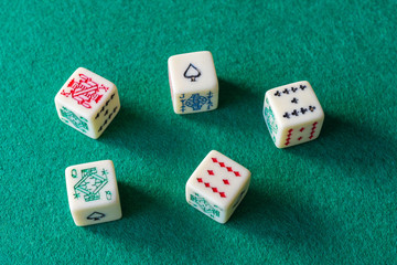 Top view of five poker dice on green mat to play, horizontal