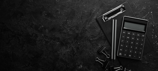 Calculator and office tools on a stone black desk. Top view. Free space for your text.