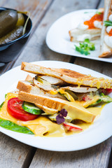 Classic breakfast, hot sandwiches with cheese, vegetables and chicken on a wooden table. Hand-made, rustic breakfast, toast with turkey and vegetables. Soft focus.