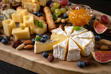 Wooden board with different types of cheese, nuts, berries and fruits. Wine snack