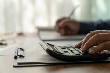 Businessman working on desk office with Investors are calculating on calculator investment costs.