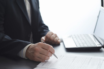 Obraz premium Manager works at a laptop in the office. Businessman makes an online transaction. Trading on the exchange via the Internet.