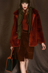 girl in a beautiful brown fur coat posing in the Studio on a brown background