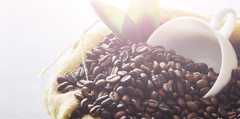 Coffee beans with green leaves for cooking. Bag of coffee. Coffee beans roasted on the table.