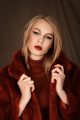 girl in a beautiful brown fur coat posing in the Studio on a brown background