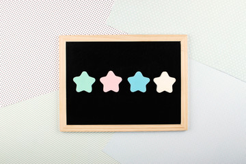 Feedback, vote, Rating, review concept. Four pastel Star Shapes on blackboard nameplate on light