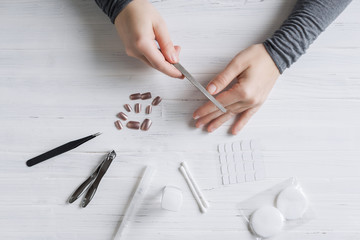 The process of putting artificial (fake) fingernail on the finger. Woman manicure. Flat lay.