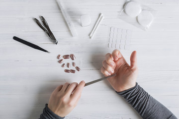 The process of putting artificial (fake) fingernail on the finger. Woman manicure. Flat lay.