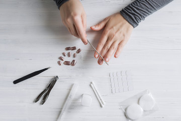 The process of putting artificial (fake) fingernail on the finger. Woman manicure. Flat lay.