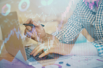Multi exposure of forex graph with man working on computer on background. Concept of market...