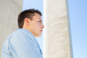 Pensive serious student guy standing outside and looking away. Outdoor portrait of handsome young...