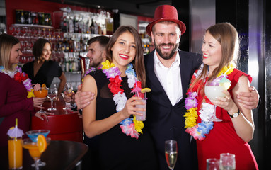 Guy with two girls on Hawaiian party in bar