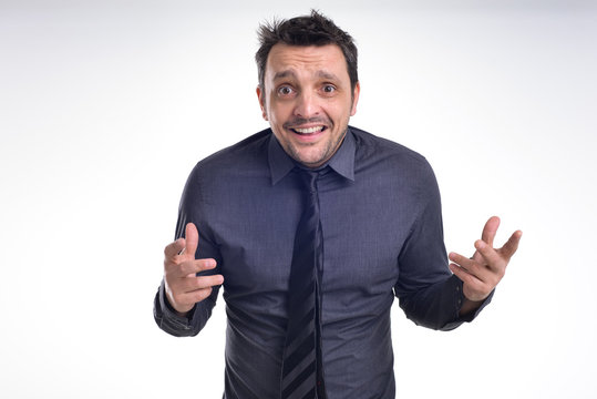 Portrait of a young dude isolated on white, wearing a grey shirt and a black tie acting excited, surprised, pulling faces .