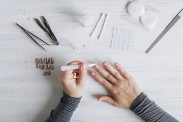 The process of putting artificial (fake) fingernail on the finger. Woman manicure. Flat lay.