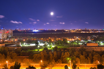 Fototapeta na wymiar Night city panorama with urban landscape and illuminated buildings under moon and night sky. Kiev