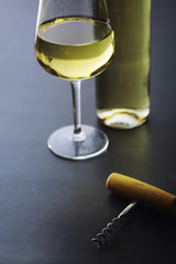 Transparent bottle of white dry wine on the table. White wine glass on a wooden background.