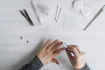 The process of putting artificial (fake) fingernail on the finger. Woman manicure. Flat lay.