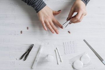 The process of putting artificial (fake) fingernail on the finger. Woman manicure. Flat lay.